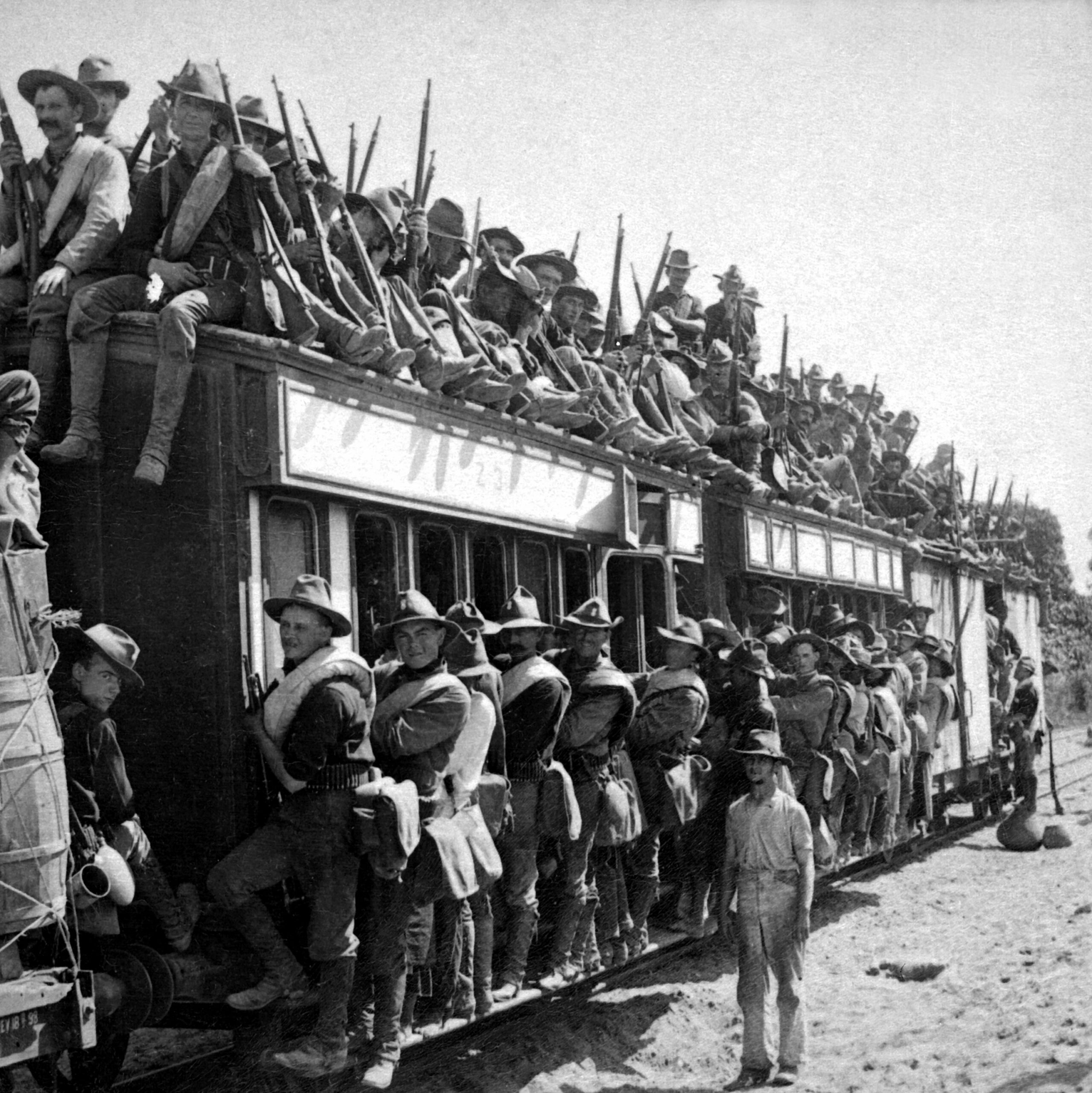 Soldater klättrar på utsidan av överfyllda tågvagnar under mobiliseringen inför första världskriget.