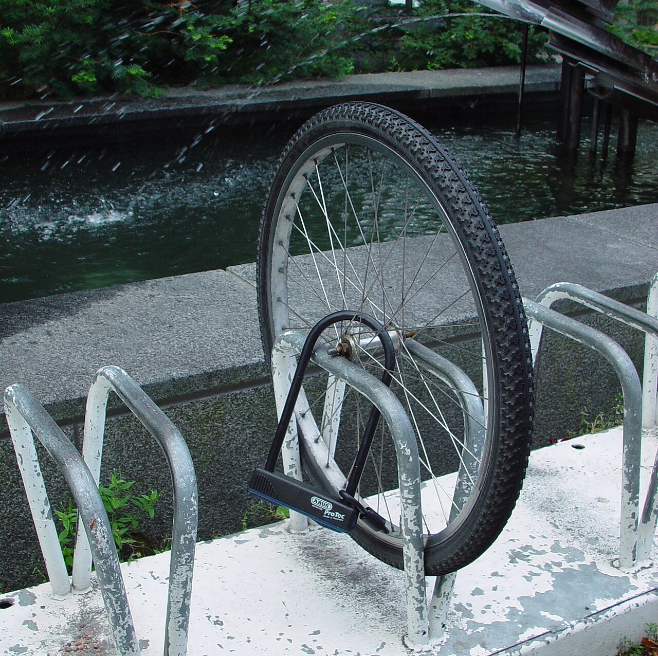 Framhjul från en stulen cykel fastlåst vid cykelställ.