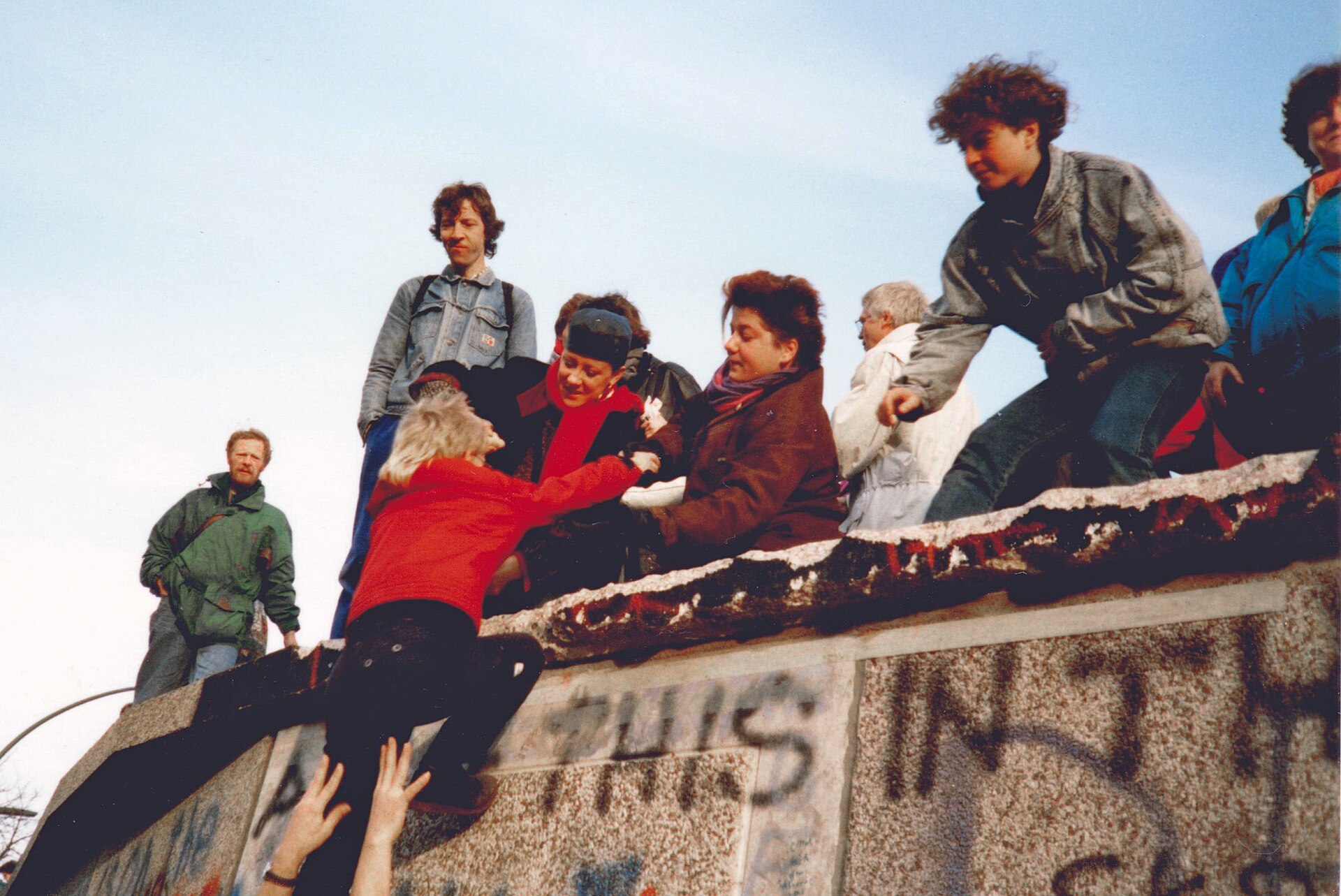 Människor klättrar över Berlinmuren i november 1989.