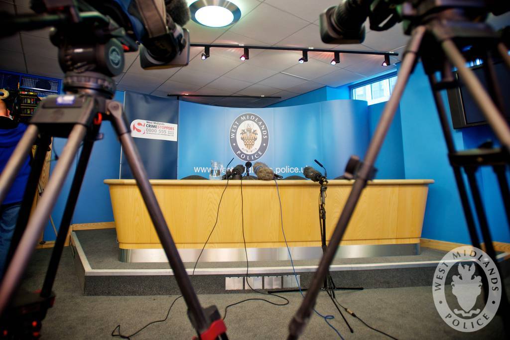 Ett tomt presskonferensrum hos polisen med stolar, bord och mikrofoner.