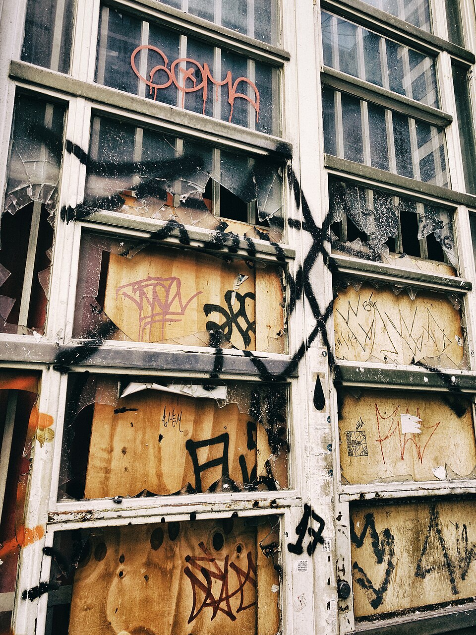 Vandaliserad byggnad med krossade fönster och graffiti.